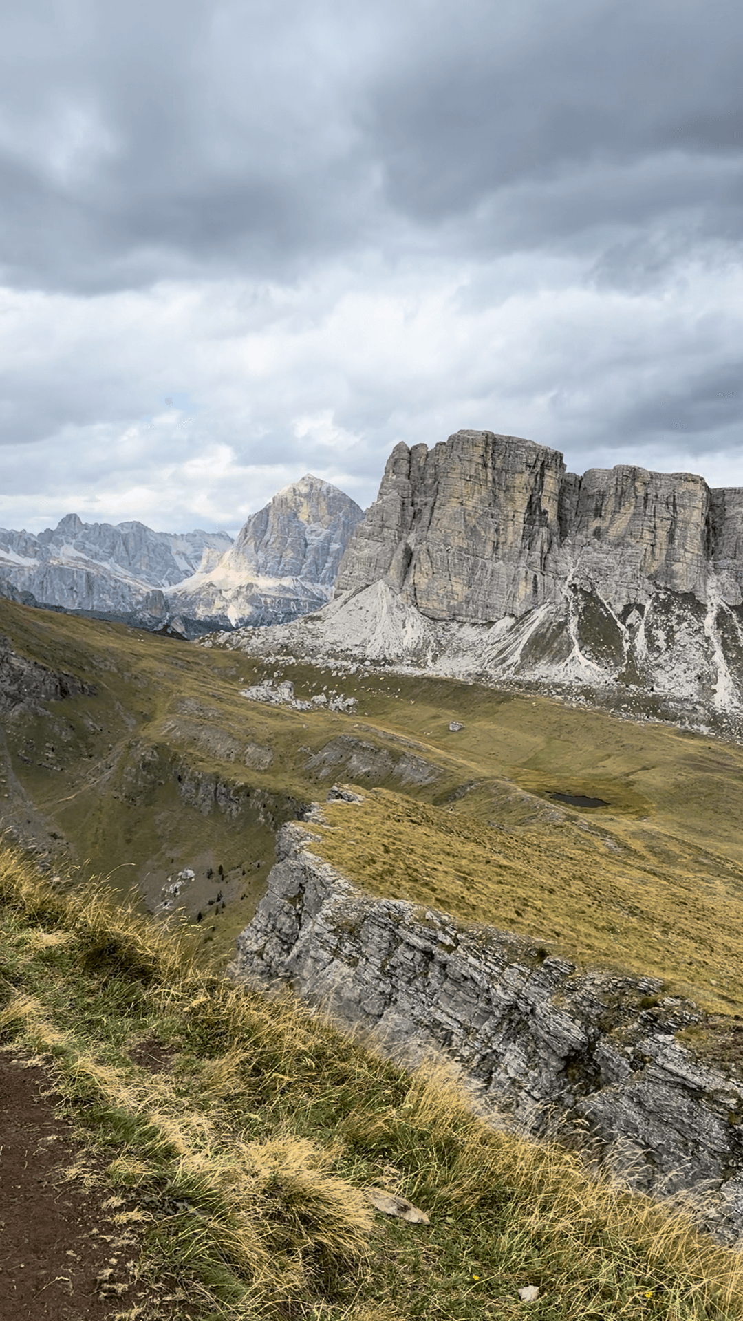 Rugged mountain peaks with rocky cliffs and grassy alpine valley under cloudy sky
