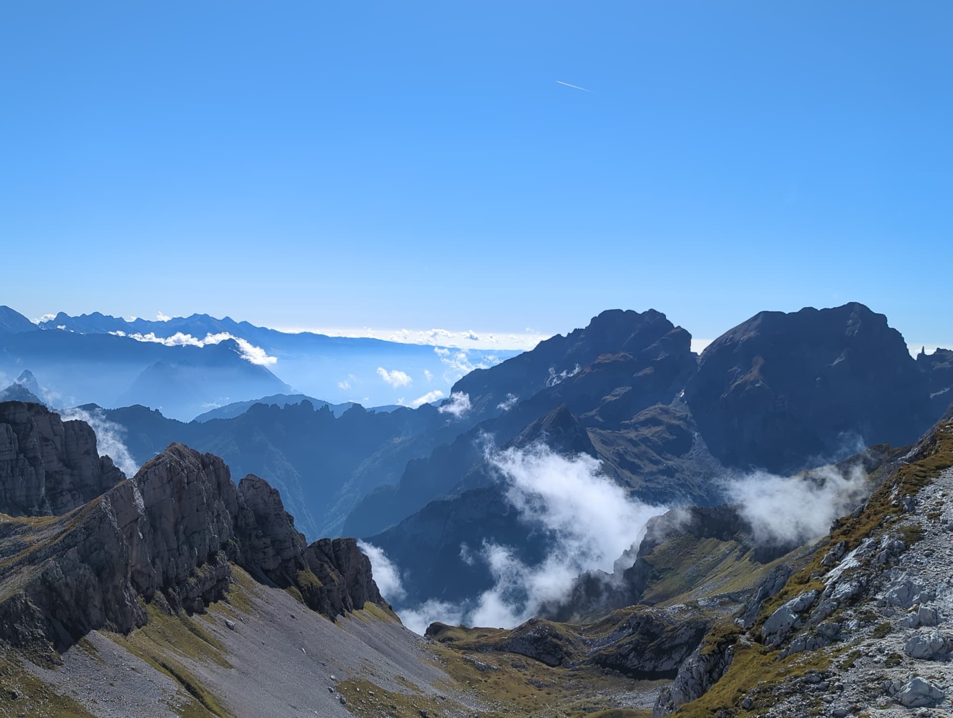 Alpine mountain peaks rising above a sea of clouds under a clear blue sky