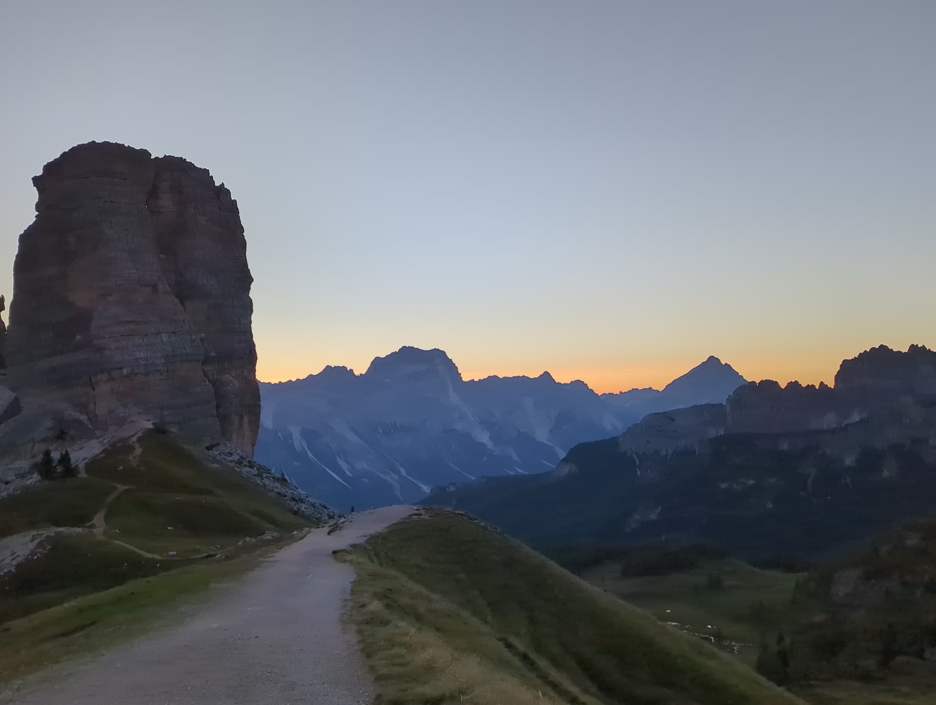 Hiking trail with rock tower at dusk in alpine mountain landscape