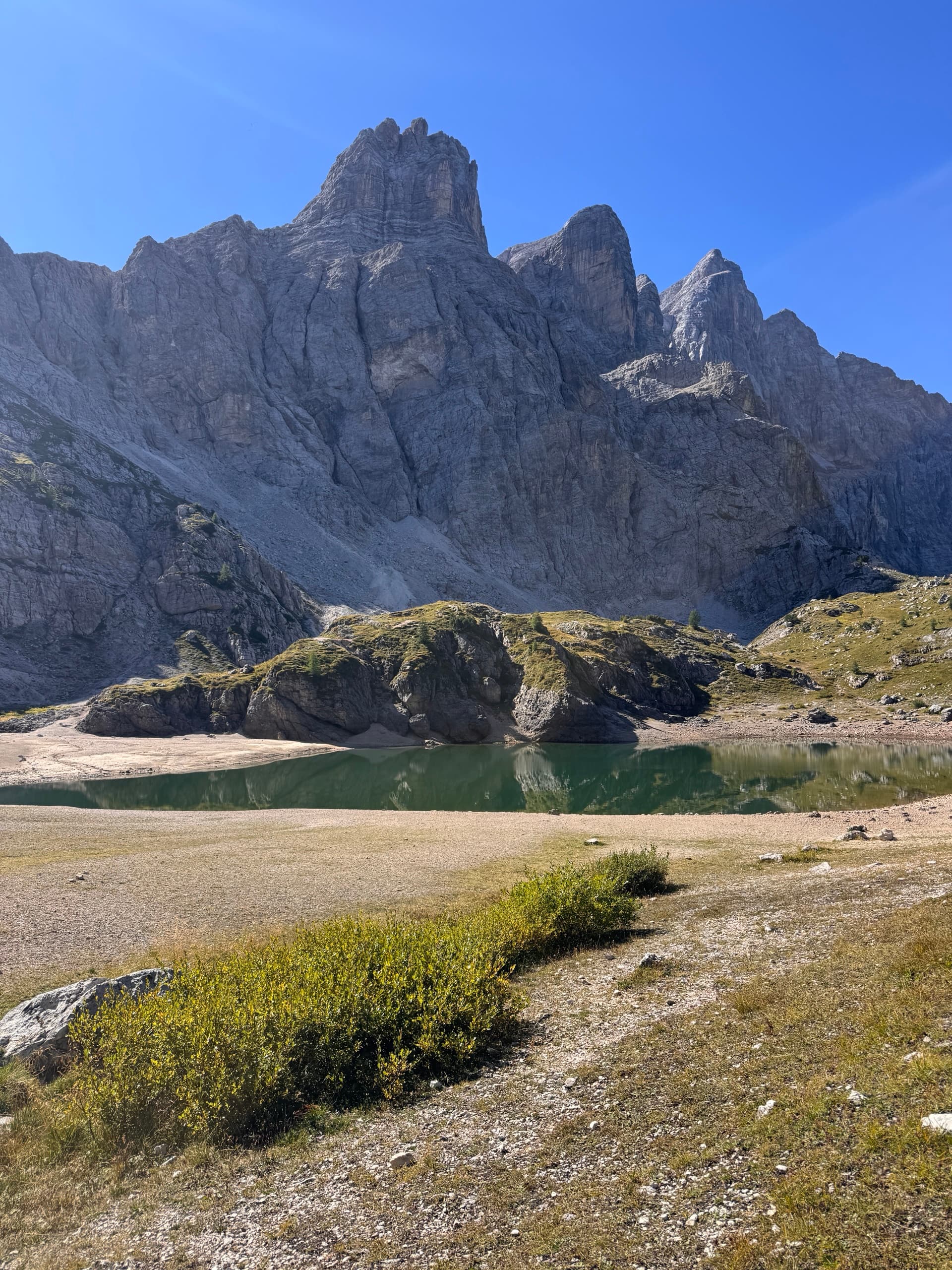 Jagged mountain peaks rising above a small alpine lake with sparse vegetation