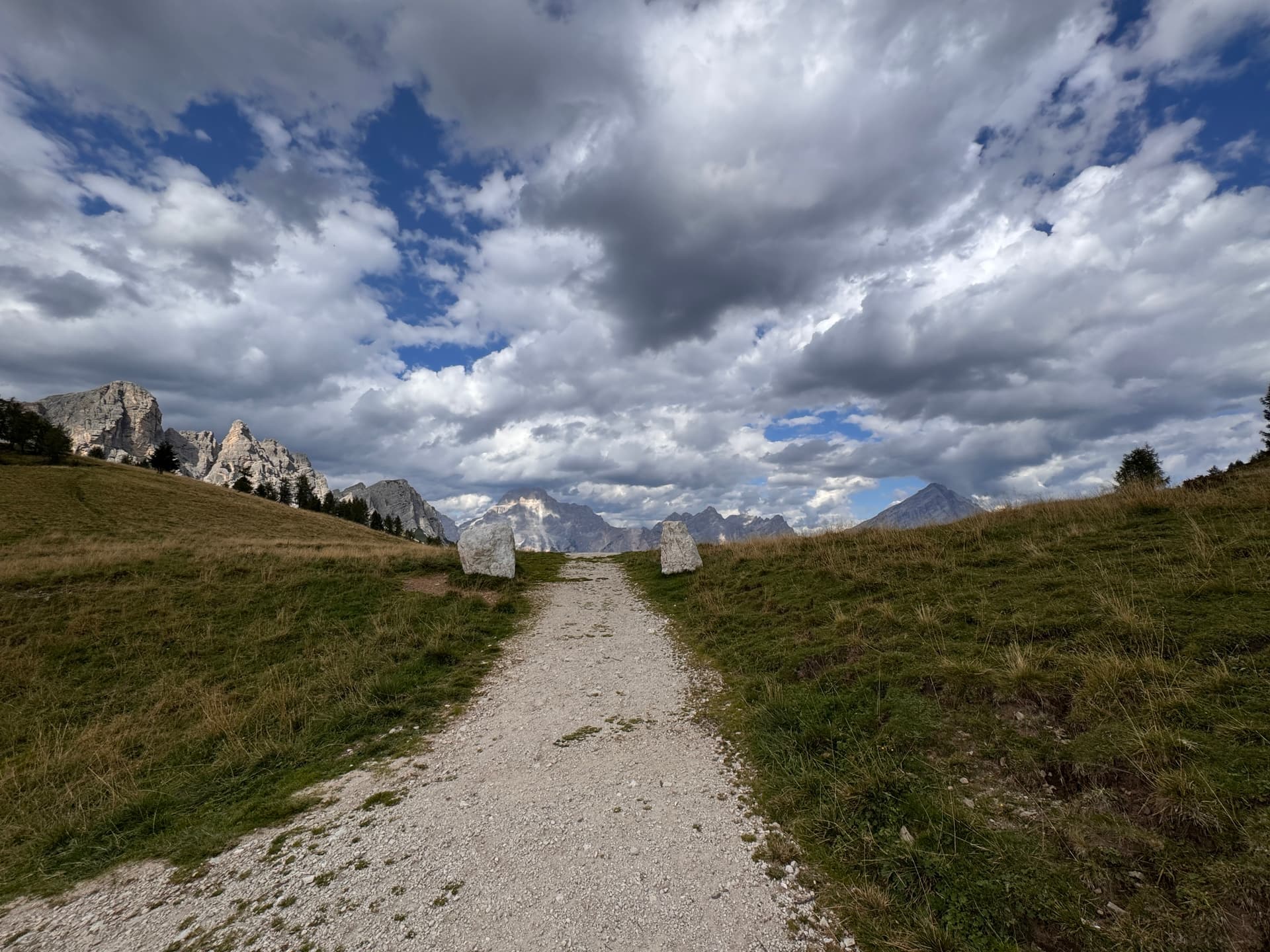 Hiking track across a high plateau with mountain peaks and cloudy sky