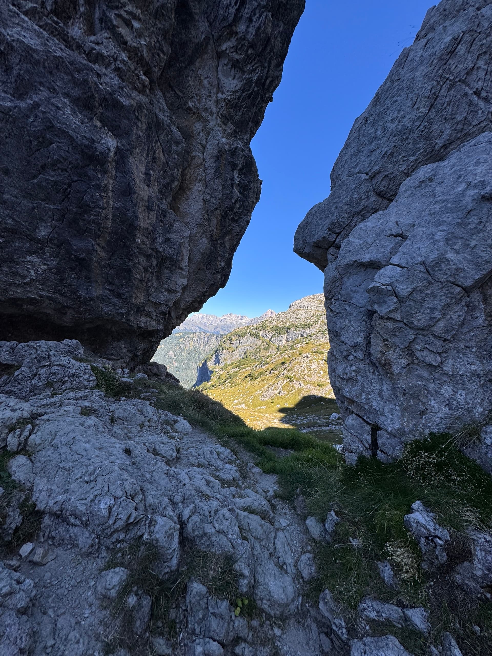 Mountain landscape viewed through a gap between rocky boulders under blue sky