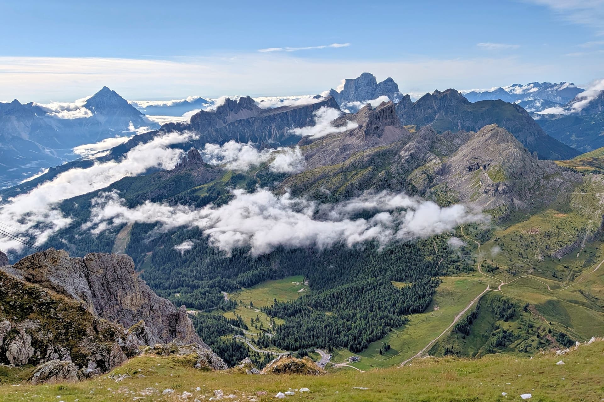 Alpine mountain peaks rising above morning clouds and green valleys