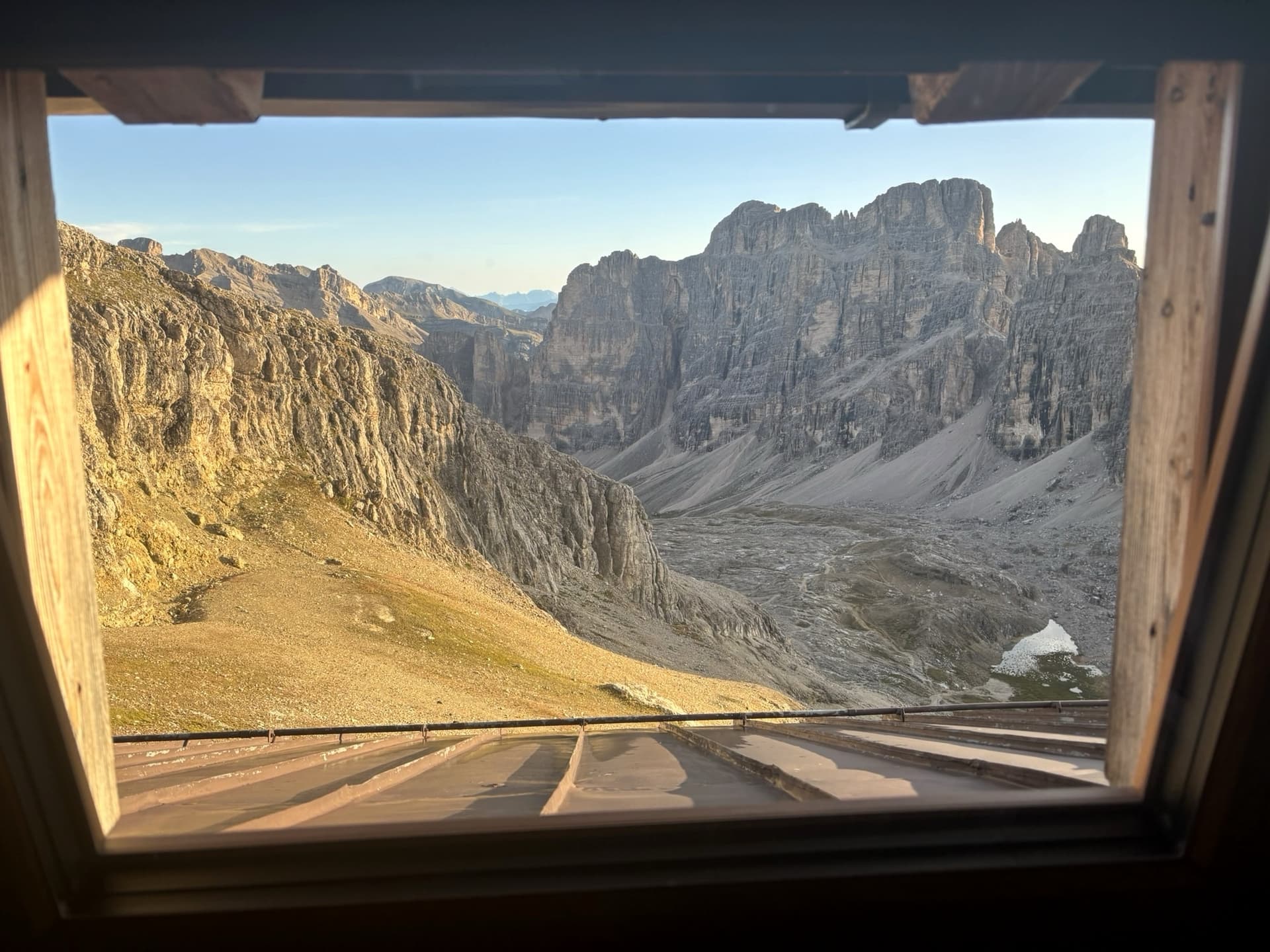 Alpine mountain peaks framed by a wooden hut window